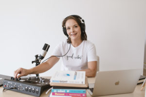 Picture of Emily at her Podcast table with microphone